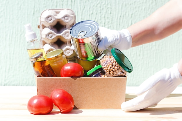 Foto il volontario riempie una scatola di cartone per alimenti essenziali