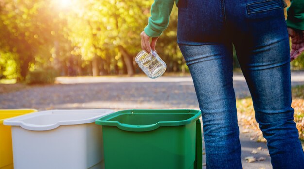 Photo volunteer girl sorts garbage in the street of the park. concept of recycling.