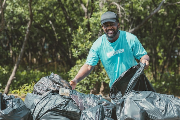 Volunteer man clean up garbage waste in the forest for ecology in Earth day