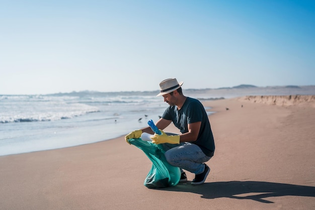 Volunteer man collects plastic waste on the beachx9