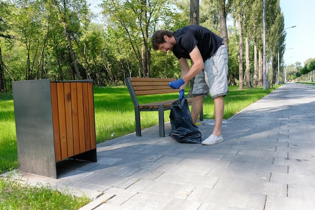 A volunteer man picking up trash in a city park. Pollution of nature environmental problems