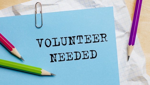 Photo volunteer needed text written on a paper with pencils in office