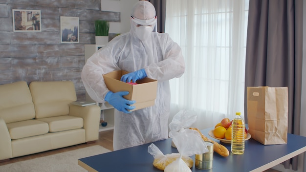 Volunteer organising food wearing protective suit during covid pandemic.