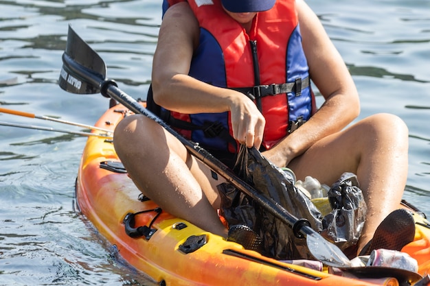 Persona volontaria in kayak che raccoglie rifiuti e plastica nell'oceano