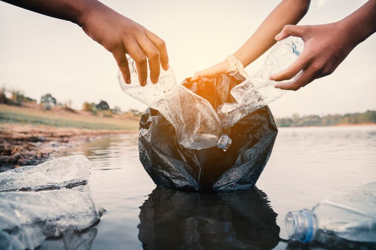 Photo 川でペットボトルのプラスチックを拾うボランティアは、汚染の概念から環境を守ります。