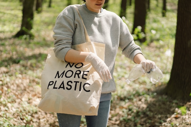 Волонтер убирается в лесу Женщина собирает пластик