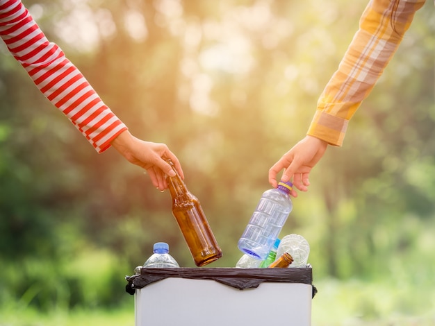 Volunteer women collect plastic water bottles in the park area