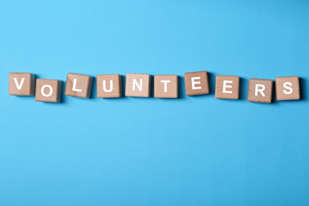 Volunteering concept Wooden cubes on color background