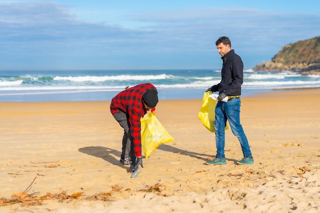 Volunteers collecting plastic from the sand on the beach\
ecology concept sea pollution