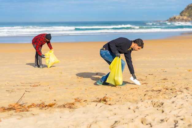 浜辺の砂からプラスチックを集めるボランティア 生態学の概念 海洋汚染