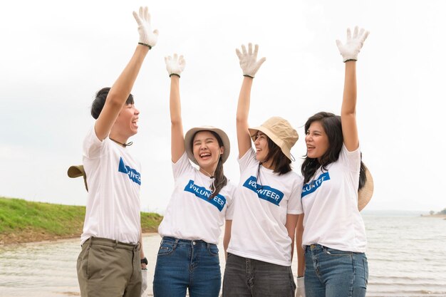 Photo volunteers from the asian youth community using rubbish bags cleaning up nature par