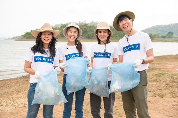 Volontari della comunità giovanile asiatica che usano i sacchi della spazzatura per ripulire la natura par