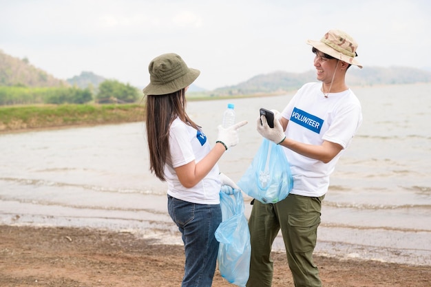 Volontari della comunità giovanile asiatica che usano i sacchi della spazzatura per ripulire la natura par