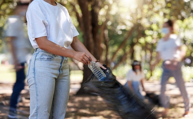 Volunteers helping collect trash on community cleanup project outdoors collecting plastic and waste to recycle Woman cleaning environment picking up dirt in street People uniting to make a change