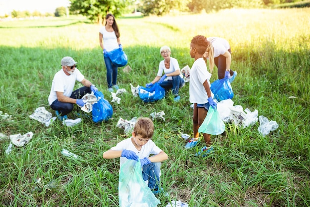 Volunteers with garbage bags cleaning up garbage outdoors - ecology concept.