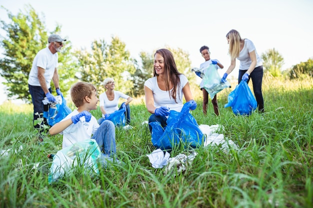 Volunteers with garbage bags cleaning up garbage outdoors - ecology concept.