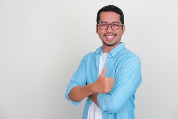 Volwassen Aziatische man die lacht trots met gekruiste armen en duim opgeeft