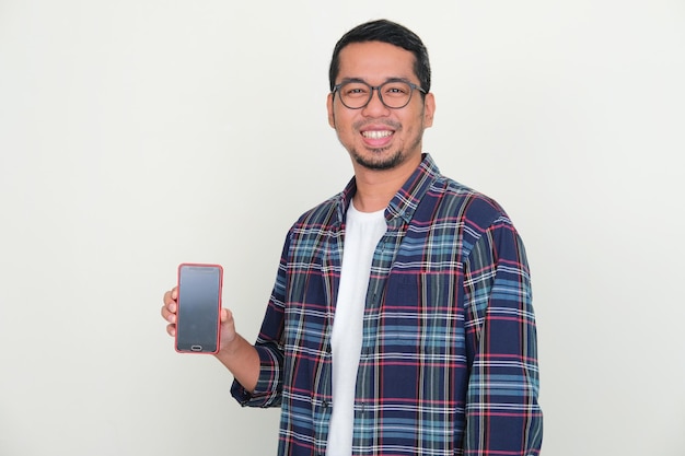 Volwassen Aziatische man die zelfverzekerd naar de camera glimlacht terwijl hij een leeg scherm van een mobiele telefoon laat zien