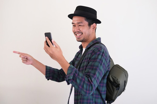 Volwassen Aziatische man wijst met de vinger naar voren terwijl hij op de kaart kijkt met zijn mobiele telefoon tijdens het reizen