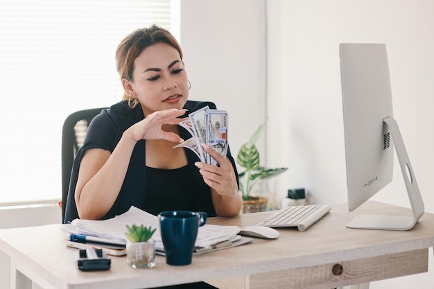 Volwassen Aziatische vrouw zittend op een bureau en contant geld tellen