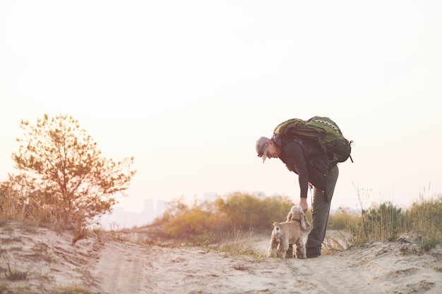 Volwassen backpacker buigt voorover voor hond