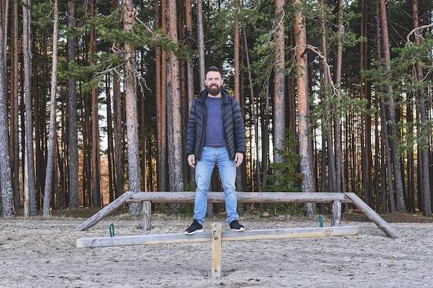 Volwassen bebaarde man hipster die op een schommel blijft in een speelplaats in het bosconcept van geestelijke harmonie an