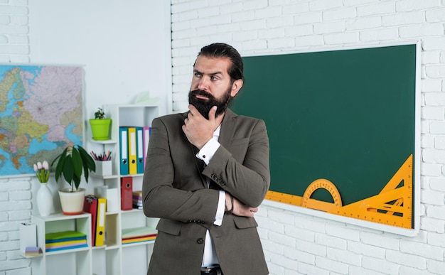 Volwassen bebaarde man met baard en snor draagt een pak in het klaslokaal op school