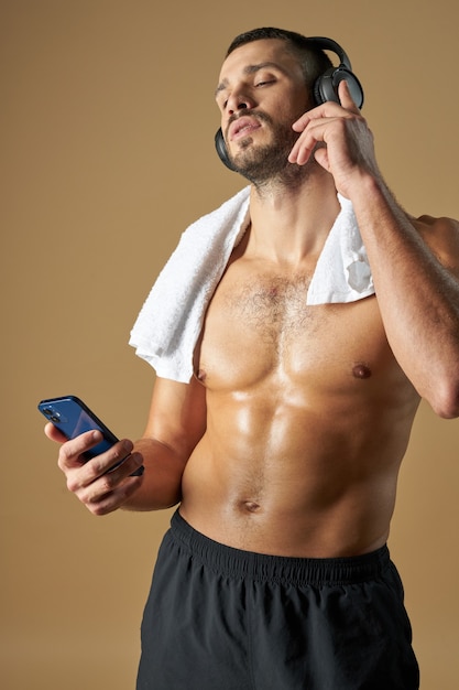 Volwassen blanke atleet met smartphone in de hand geïsoleerd op gele achtergrond