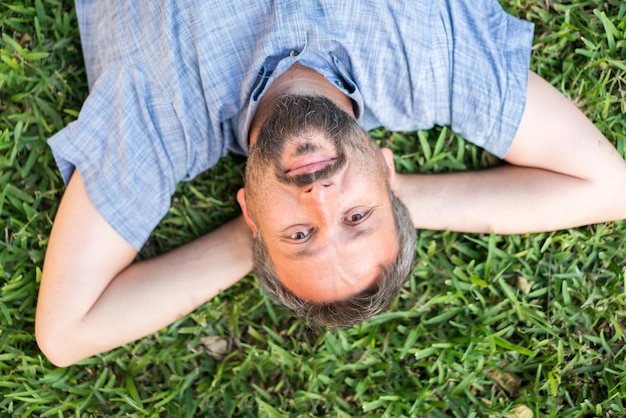 Volwassen blanke man liggend ondersteboven portret op gras weide