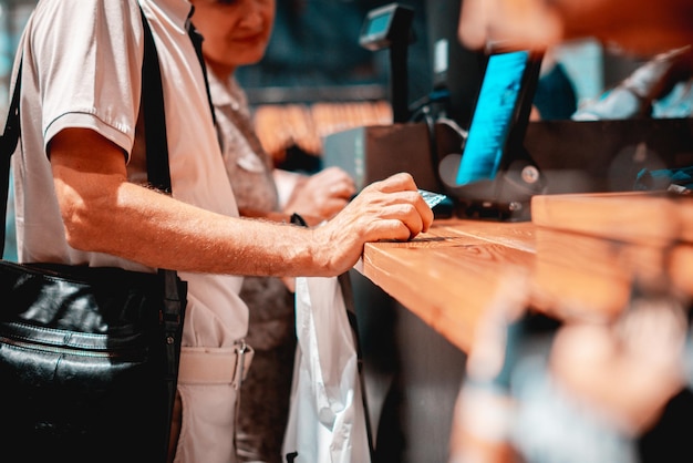 Volwassen consument die met creditcard betaalt in de winkel met een portemonnee s