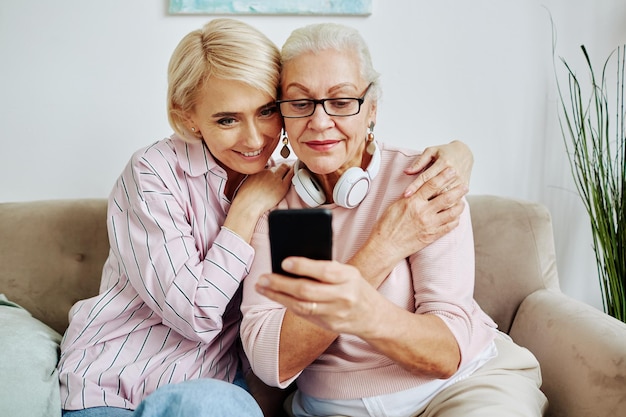 Volwassen dochter helpt oudere vrouw met mobiele telefoon