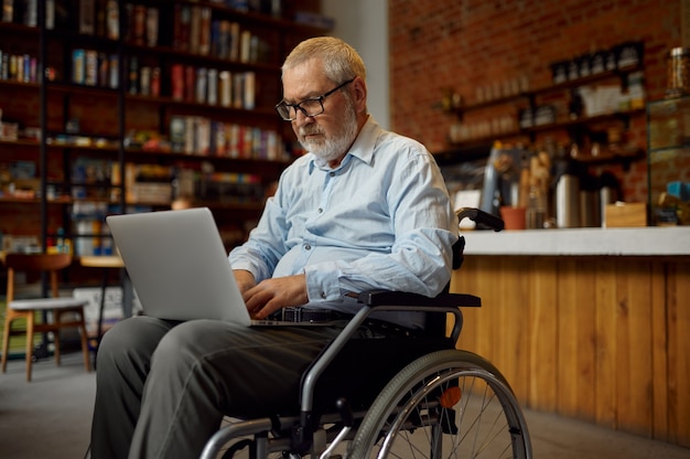 Volwassen gehandicapte man in rolstoel met laptop