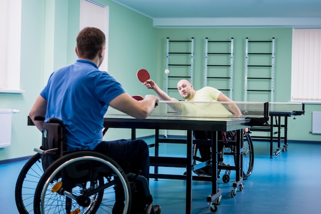 Volwassen gehandicapte mannen in een rolstoel die tafeltennis spelen