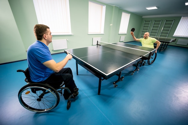 Volwassen gehandicapte mannen in een rolstoel die tafeltennis spelen