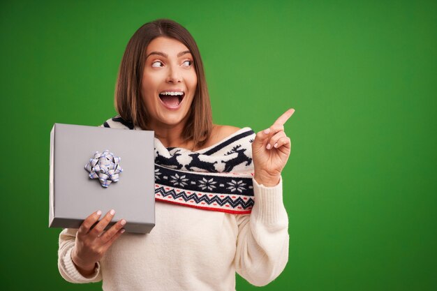 Volwassen gelukkige vrouw met kerstcadeau over groene achtergrond