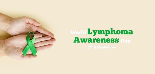 Volwassen handen houden groen lint op beige achtergrond Wereldlymfoombewustzijnsdag 15 september
