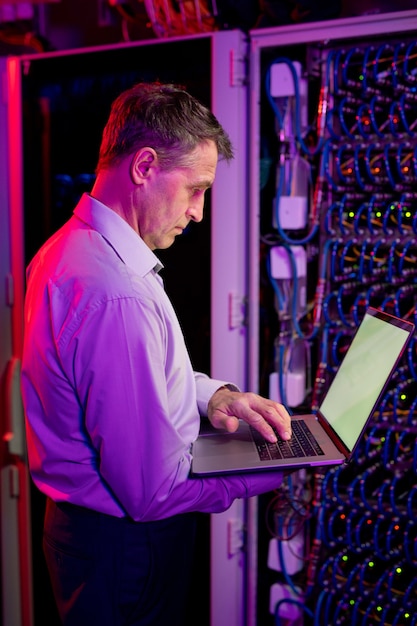 Volwassen IT-ingenieur die met laptop werkt