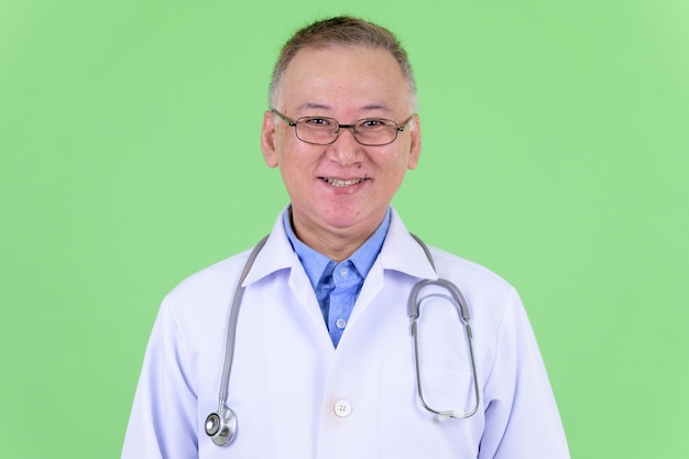 volwassen Japanse man arts met bril tegen Chromakey met groene muur