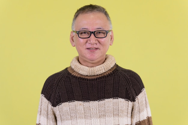 volwassen Japanse man met coltrui klaar voor de winter tegen chroma key met groene muur