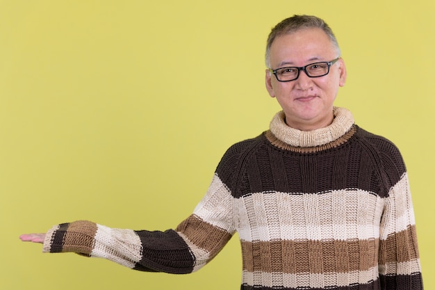 volwassen Japanse man met coltrui klaar voor de winter tegen chroma key met groene muur