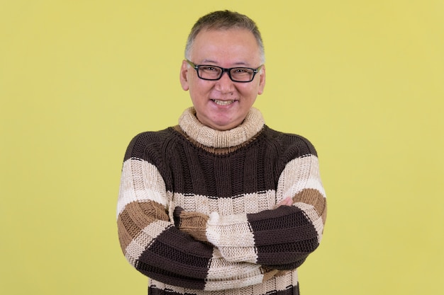 volwassen Japanse man met coltrui klaar voor de winter tegen chroma key met groene muur