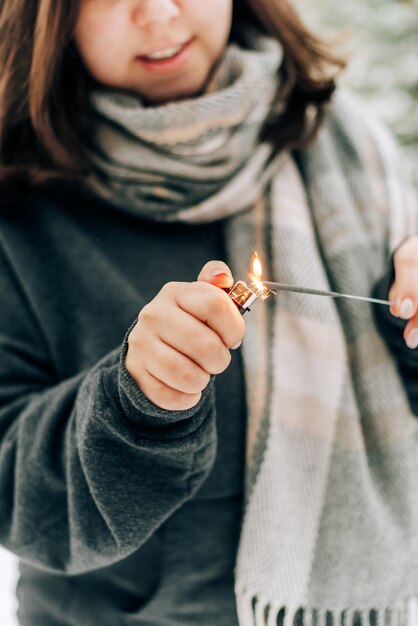 Volwassen jonge vrouw met wonderkaarsen op het dennenbos van de winter