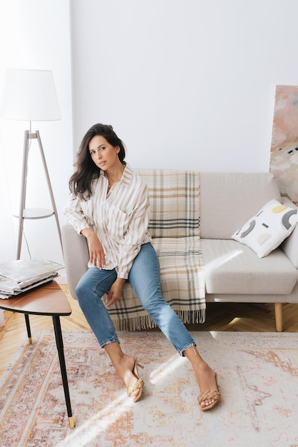 volwassen jonge vrouw rust in mooie vrouwelijke blauwe jurk in een lichte kamer bij het raam relax