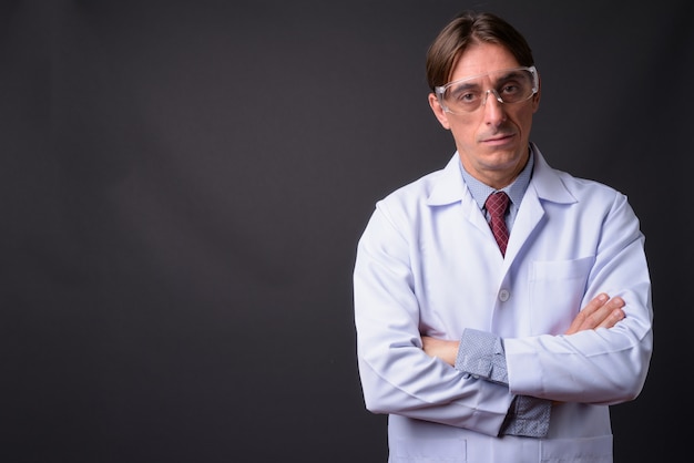 volwassen knappe Italiaanse man arts beschermende bril tegen grijze muur