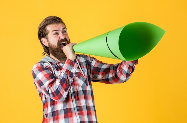Volwassen knappe man in geruit hemd spreekt in papieren luidspreker, advertentie.