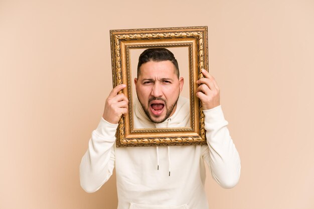 Volwassen Latijnse man die een vintage frame vasthoudt en geïsoleerd glimlacht
