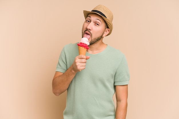 Volwassen Latijnse mens die een roomijs eet dat op beige achtergrond wordt geïsoleerd