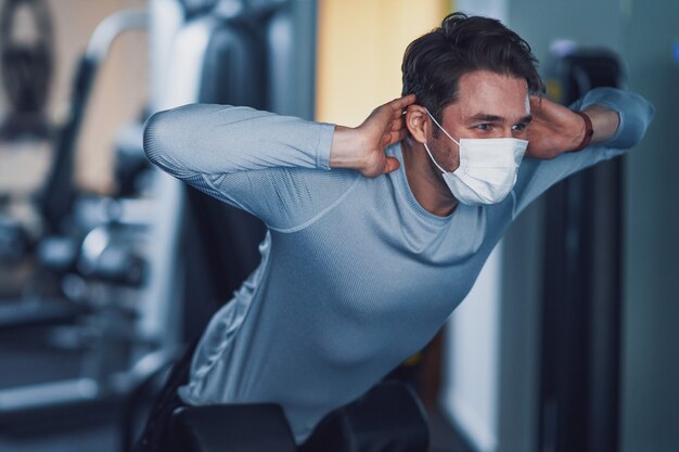 Volwassen man aan het trainen in een sportschool met masker vanwege covid-19