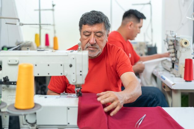 Volwassen man aan het werk in een naaiatelier naast een collega