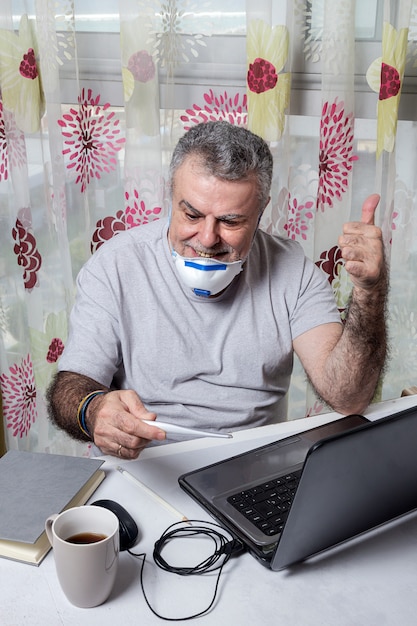 Volwassen man aan het werk thuis met beschermend masker